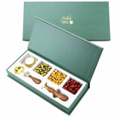 an assortment of condiments in a green box with gold spoons and other condiments