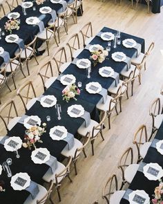 an overhead view of tables and chairs with black tablecloths, white plates and silverware