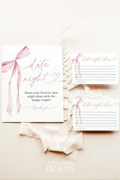 the wedding stationery is laid out on top of each other, with pink ribbons