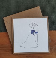 a card with a drawing of a bride and groom holding each other in their arms