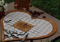 a heart shaped puzzle is laying on the ground next to some flowers and a sign