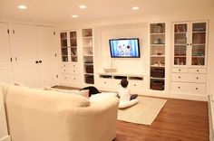 a child sitting on the floor in front of a tv and bookshelves, watching television