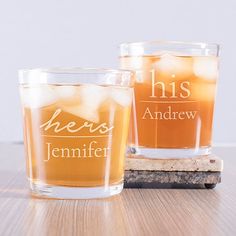 two shot glasses sitting on top of a wooden table next to each other with the words he's and she's written on them