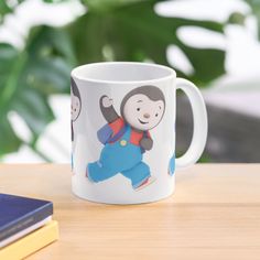 a coffee mug with a monkey on it sitting on a table next to a book