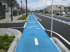 an empty street with blue painted lines on the side and buildings in the back ground