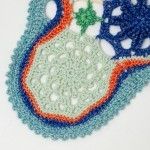 a close up of an embroidered object on a white tablecloth with blue, orange and green designs