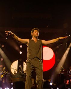 a man standing on top of a stage holding his arms out in front of him