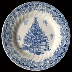 a blue and white plate with a christmas tree design on it, against a black background