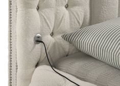 an upholstered chair with a cord plugged into the back and pillow on top