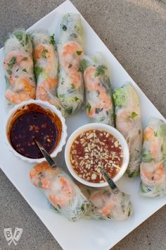 a plate full of shrimp and vegetable spring rolls with dipping sauce