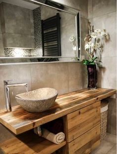 a bowl sink sitting on top of a wooden counter in front of a bathroom mirror