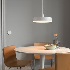 a white table with four chairs around it and a bowl of food on the table