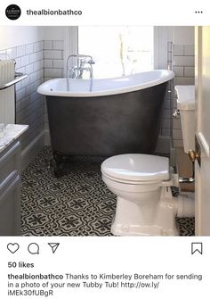 a bath tub sitting next to a white toilet in a bathroom with black and white flooring