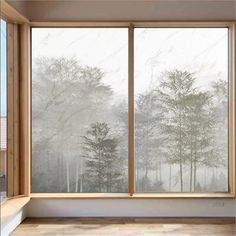 an empty room with large windows and trees outside the window, in front of a foggy forest