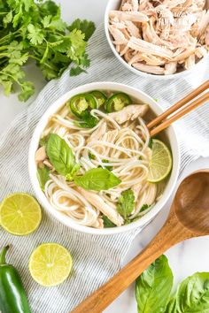 two bowls of chicken noodle soup with limes and parsley on the side