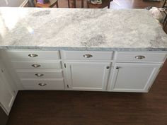 a kitchen counter top with white cabinets and drawers