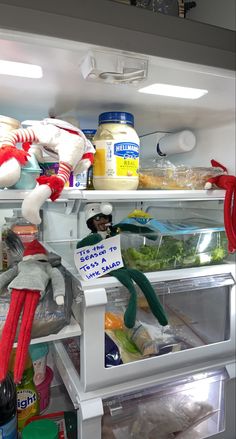 an open refrigerator filled with lots of food and stuffed animals on top of the shelves