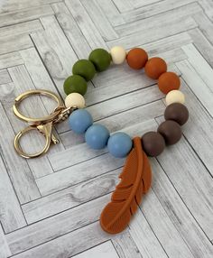 an orange, brown, and blue beaded bracelet with a feather charm on it