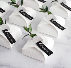 small white boxes with green leaves on them and thank you tags attached to the top