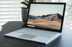 an open laptop computer sitting on top of a table next to a potted plant