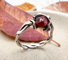 This pretty handcrafted ring has a lovely natural aesthetic. Rustic and artsy, this ring is surely one-of-a-kind and will be a unique addition to your collection. The glass bead has a warm, orangey red color that will be beautiful in any season but especially in the autumn. The ring is size 7 1/4 and has no markings. The story of this ring does not begin but continues with you. As with any well-loved piece, there are imperfections and wear picked up over its history.  Efforts have been made to take photos in bright light and to show the piece from various angles. Please examine photos closely and do not hesitate to reach out with questions! Unique Red Metal Rings, Unique Handmade Red Rings, Handmade Red Open Ring, Handmade Artisan Red Rings, Handmade Red Crystal Open Ring, Red Rings, Natural Aesthetic, Braided Ring, Warm Red