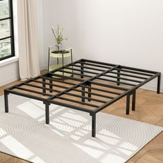 a metal bed frame sitting on top of a wooden floor next to a potted plant