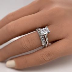 a woman's hand with a diamond ring on her left hand and an engagement band