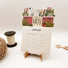 a calendar sitting on top of a wooden stand next to a spool of thread