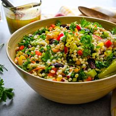 a wooden bowl filled with salad next to some spoons and utensils on a table