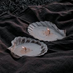 two white plates with candles in them sitting on the ground