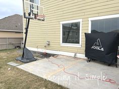 an outdoor basketball court in front of a house with a black tarp over it