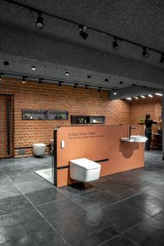 a bathroom with a brick wall and toilet in the center, surrounded by black tile flooring