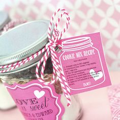 a jar filled with cookies and candy on top of a pink tablecloth covered table