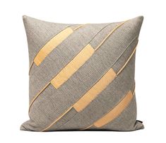 a gray and yellow pillow with gold strips on it's side, sitting against a white background