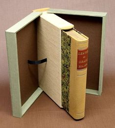 an open book in a box on a brown surface with a black ribbon around it