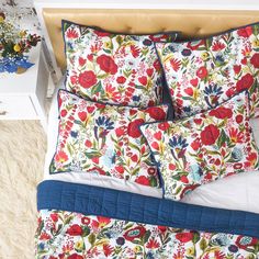 a bed with red flowers and blue trim on the comforter is shown in this image