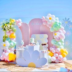 an assortment of desserts on display in front of a backdrop with flowers and balloons