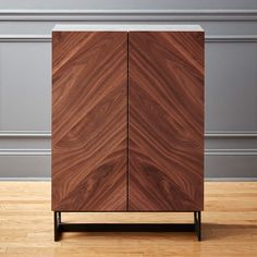 a wooden cabinet sitting on top of a hard wood floor next to a gray wall