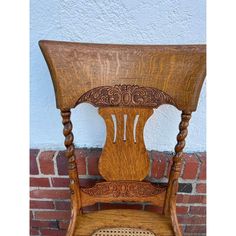 an old wooden chair sitting in front of a brick wall