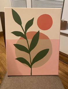 a painting on a chair in front of a window with a green leaf and orange ball