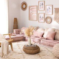 a living room filled with pink couches and pillows on top of a white rug