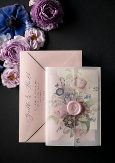 an open envelope with a button on it and flowers in the background next to it