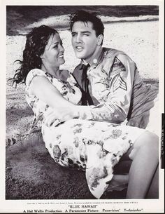 an old photo of a man and woman sitting on the ground together, smiling at each other