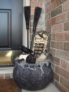 a halloween decoration in a pot on the front porch with brooms and other items