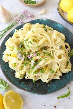 a blue plate topped with pasta next to lemons and garlic