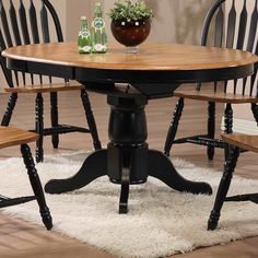 a table with four chairs around it and a vase on top of the dining room table