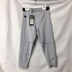 a pair of gray pants hanging on a white wall with a tag attached to it