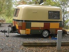 an rv parked on the side of a road in front of trees and bushes with its door open