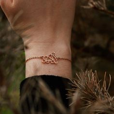 a person wearing a gold bracelet with two hearts on it