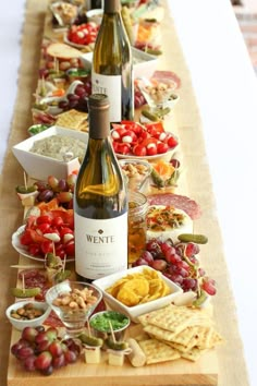 a long table with wine bottles, crackers and other food items on the table